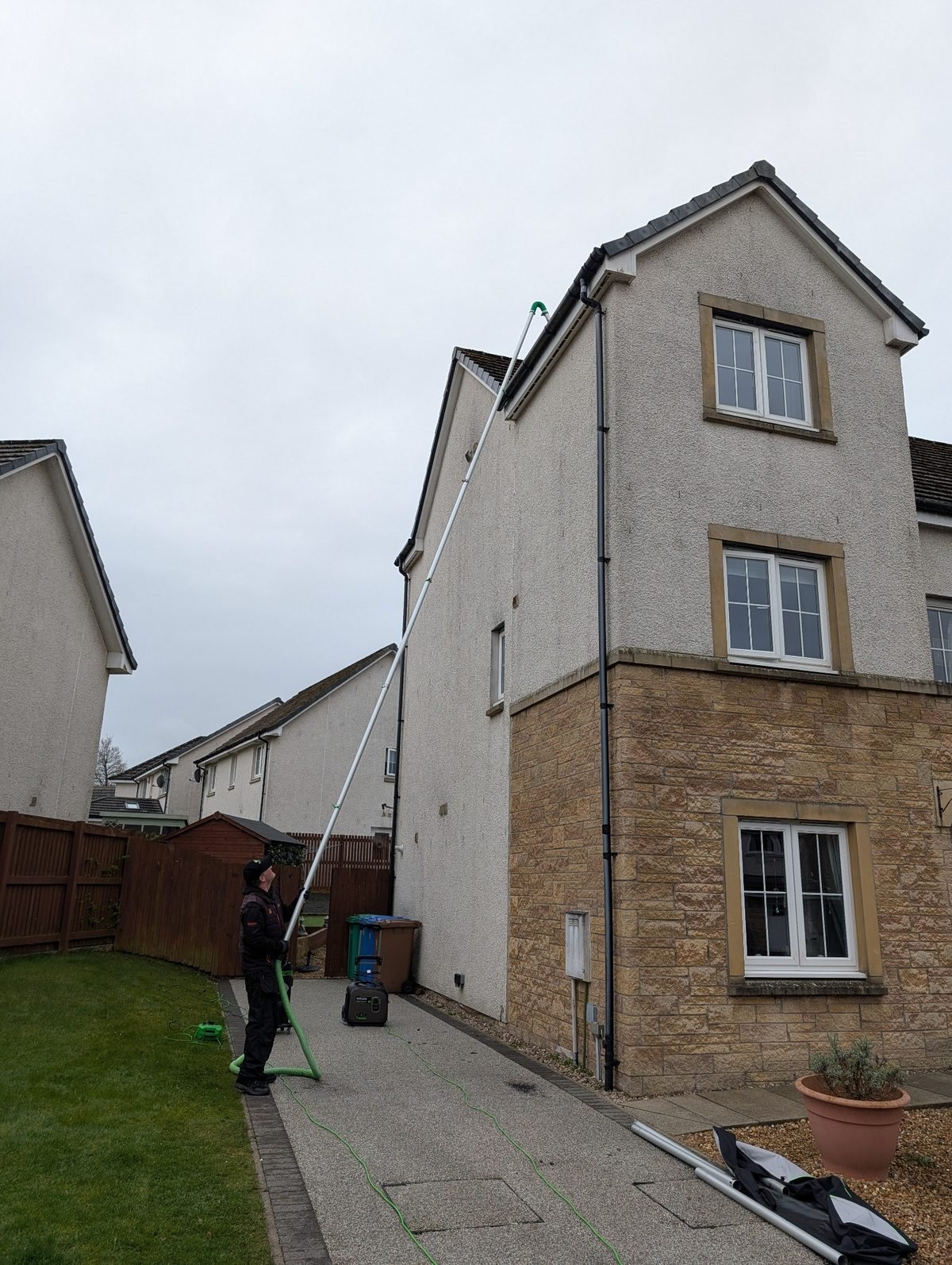 RS Window Cleaners using a high-reach gutter vacuum on a three-storey house